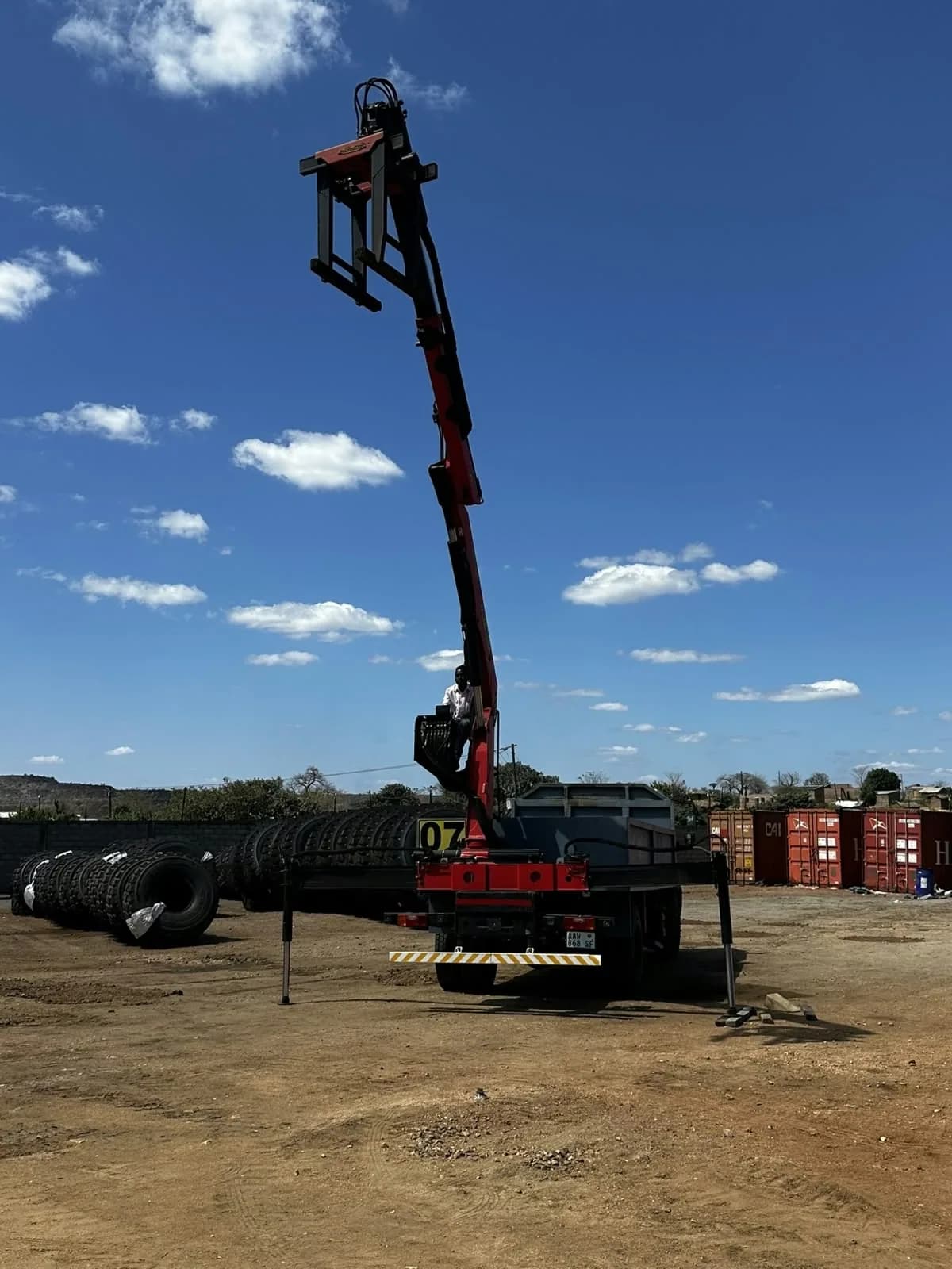 Camião com grua articulada elevada num parque de equipamentos