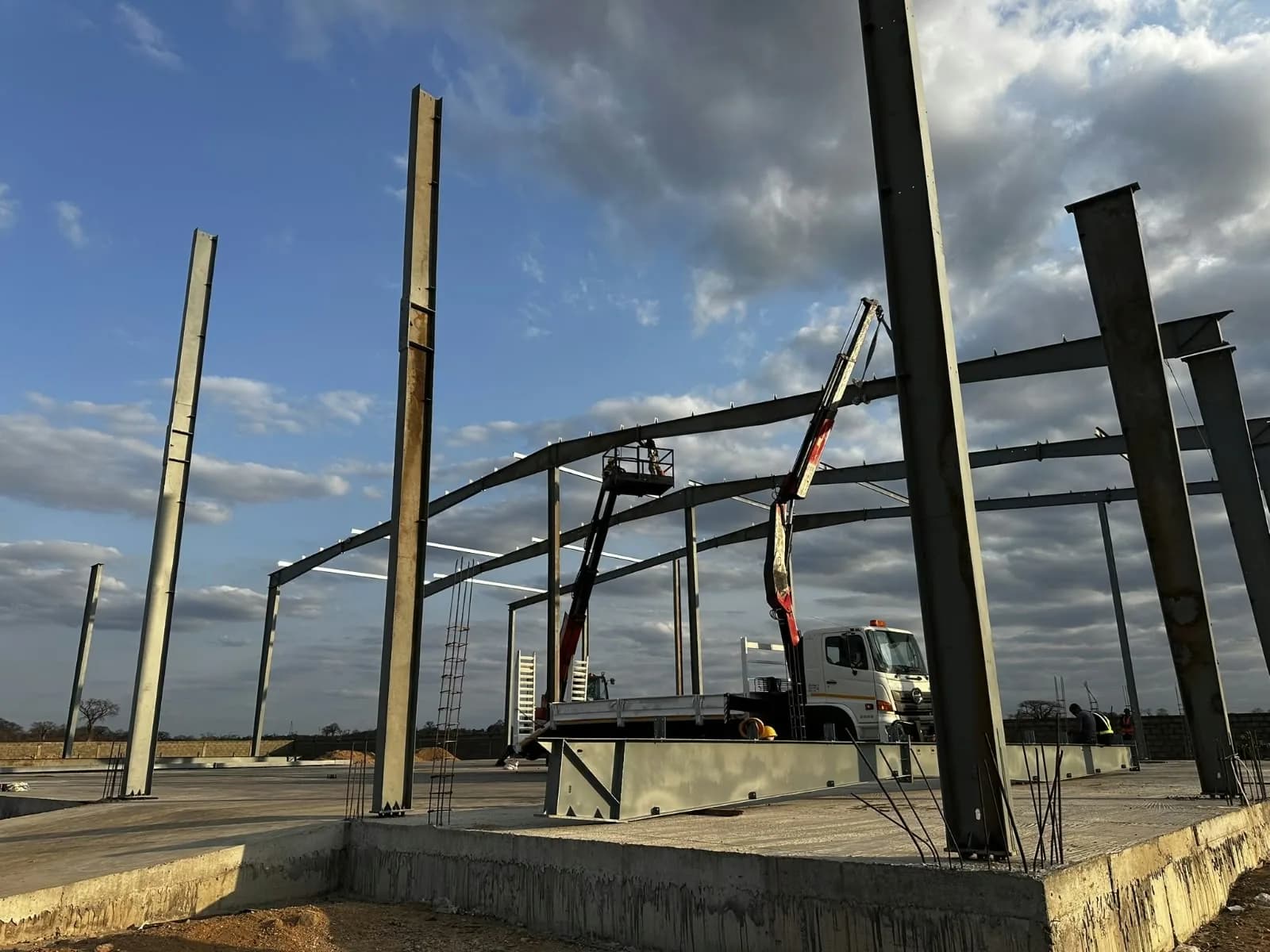 Camião com grua entre pilares metálicos sobre fundações de betão